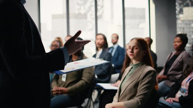 Multiethnic people asking questions and raising hand during discussion, engaging in debate and listening to convention speech. Diverse group of white collar workers attend event. Camera A.