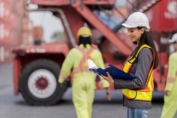 Team logistics workers in high visibility safety gear and hard hats discuss operations at a busy shipping container yard. Team multi nationality working together on site container warehouse. © ultramansk