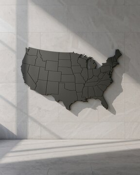 A gray map of the united states mounted on a white wall with shadows
