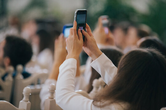 Audience member capturing event on smartphone at conference