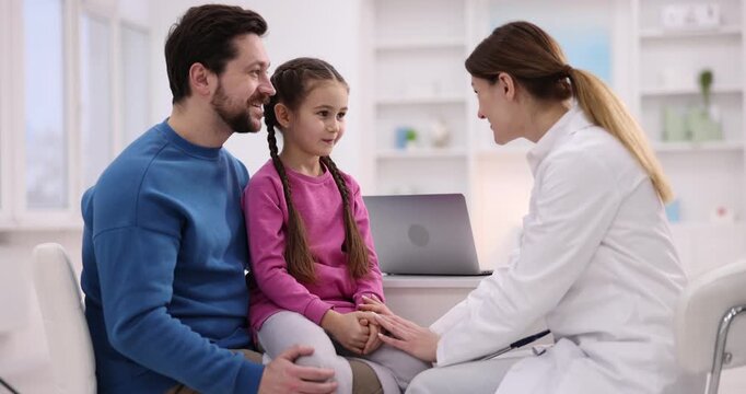 Little girl and her father having appointment with pediatrician in hospital. Doctor checking child with stethoscope