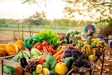 Fresh organic fruits and vegetables displayed at a local farm market at sunset with a farmer in the background. © Nexa
