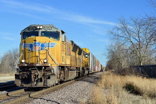 A Union Pacific freight train moves slowly westbound through north cental Illinois while approaching a crossing of a Burlington Northern Santa Fe mainline..
