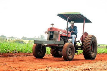 Obraz premium Farmer driving a red vintage tractor on a dirt road through agricultural fields