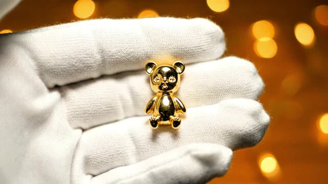 Video, close-up, hand holding gold in the shape of a teddy bear, jewelry 