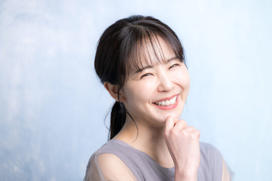 水色背景で美容やスキンケアの明るいイメージのクローズアップ　笑顔で考えるカメラ目線