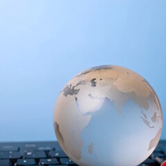 Fototapeta premium Glass Globe on Keyboard Symbolizing Global Connectivity and Digital Communication.