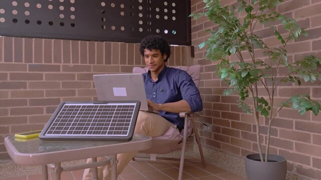 Young man using a laptop powered by a portable solar panel charger