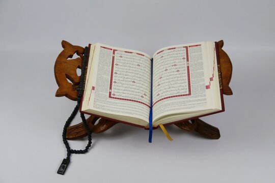 Open Quran on Wooden Prayer Stand with Colorful Tasbih and Bookmark. Ramadan and Islamic concept. isolated on white background