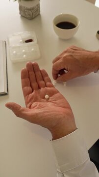 Elderly man's hands taking daily vitamin pills and supplements