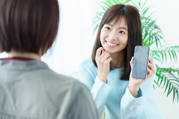 スマートフォンの画面を見せる女性