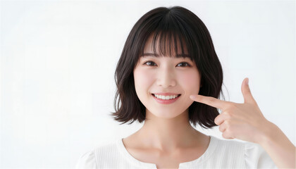 歯を指差して微笑むボブヘアの若い日本人女性