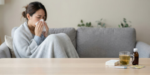 Home woman winter disease health with korean season unhealthy ache allergy asia autumn blanket blowing sneeze on sofa under gray throw feeling cold and lonely