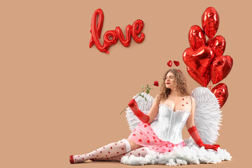 Fototapeta premium Sexy young woman dressed as Cupid with rose and balloons on cloud against beige background. Valentine's Day celebration