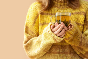 Young woman with glass cup of green tea on beige background, closeup