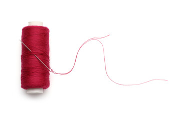 Red sewing thread with needle on white background