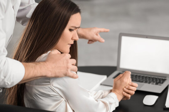 Young man molesting his female colleague at desk in office. Harassment concept