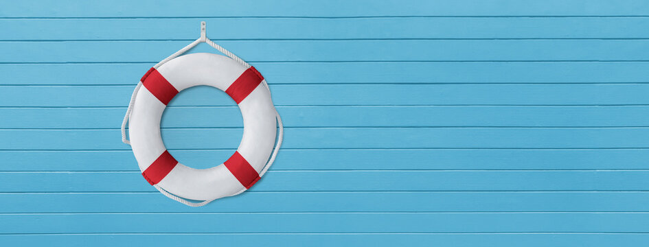 Life buoy on the pier, White life buoy with red stripes and white rope around hanging on blue wooden wall, Used to help people who have fallen into water or are drowning
