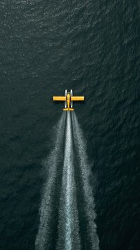 Yellow seaplane flying over dark water