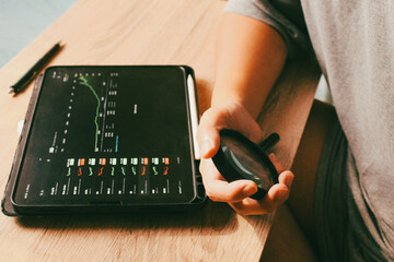 Person holding magnifying glass analyzing financial stock market charts on tablet, concept of investment research and data verification.