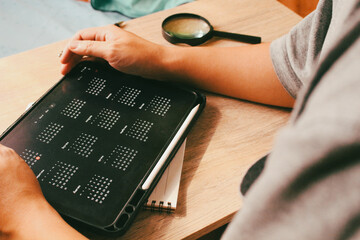 Businessman analyzing annual calendar on digital tablet with magnifying glass, concept of long-term planning and schedule inspection.