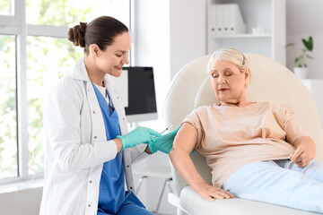 Obraz premium Senior woman receiving vaccine from doctor on couch in clinic