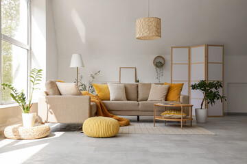 Interior of stylish living room with cozy grey sofa, coffee table and houseplants