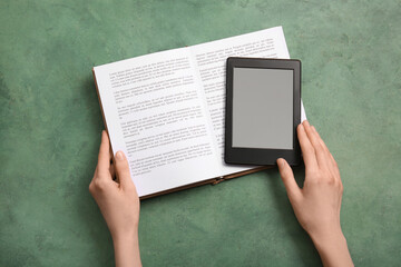 Female hands with modern e-reader and book on green grunge background