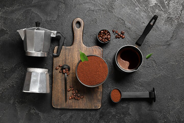 Composition with bowl, coffee powder and geyser coffee maker on black grunge background, closeup