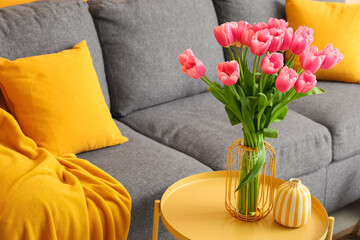 Fototapeta premium Vase with bouquet of beautiful tulip flowers and books on coffee table in living room, closeup