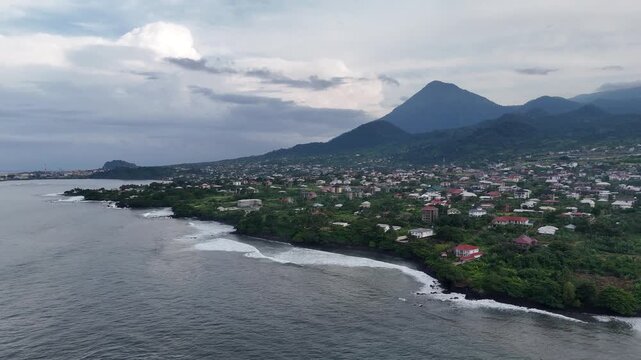 A high-angle drone perspective of the coastal city of Limbe, Cameroon, with the majestic Mount Cameroon rising in the misty background
