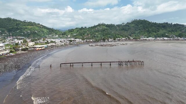 A high-angle aerial perspective showing the intersection of the Atlantic coastline and the developing town of Limbe, highlighting the unique dark sand beaches in Cameron Africa
