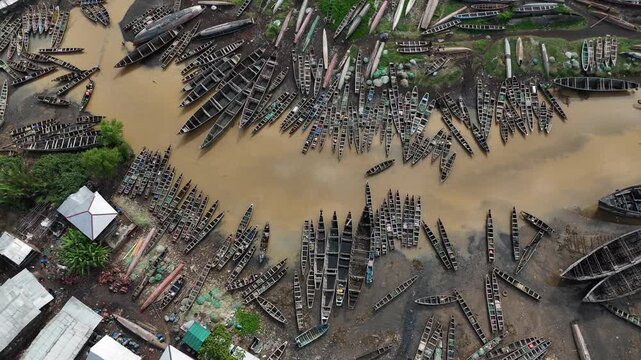 drone top down showing the tightly packed buildings of Limbe, nestled between tropical greenery and the Atlantic coast with traditional wooden fisherman boat on the river