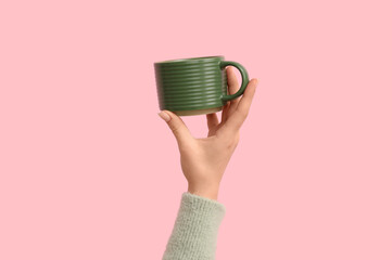 Fototapeta premium Female hand with green ceramic mug on pink background