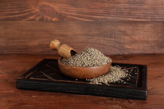Board with bowl of dried anise seeds and scoop on wooden background