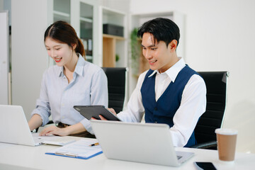 Obraz premium Business coworkers collaborating at office desk using laptop and tablet. Professional teamwork, corporate meeting, digital strategy, productivity