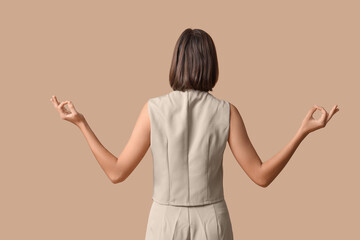 Obraz premium Pretty young woman meditating on beige background, back view