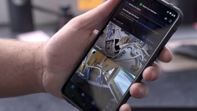 A Close-up of a hand holding a smartphone showing multiple live security camera feeds