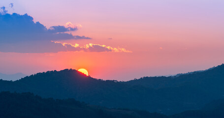 Obraz premium Soft pastel sunset behind mountain silhouettes creating a peaceful and dreamy atmosphere.