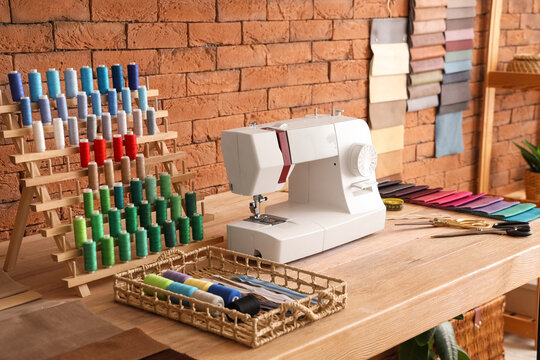 Tailor's workplace with sewing machine and thread spools in atelier