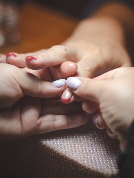 Nail technician applies nourishing cuticle oil after completing nail extension to moisturize the skin