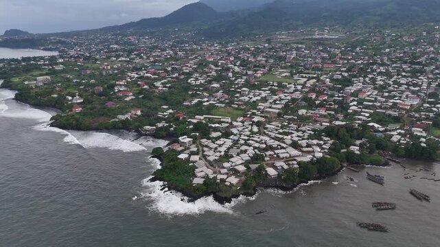 Capturing the tropical urban landscape of Limbe from above, this drone footage highlights the vast proximity of the city to the Atlantic Ocean under a misty sky