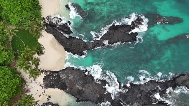 Capturing the raw natural beauty of the Gulf of Guinea where dense tropical jungle meets the crystal-clear sea. Aerial view of turquoise waves crashing against the volcanic shore of Sao Tome