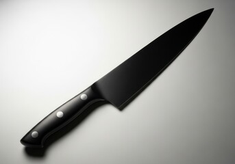 Obraz premium A black kitchen knife with a sleek handle on a gray surface