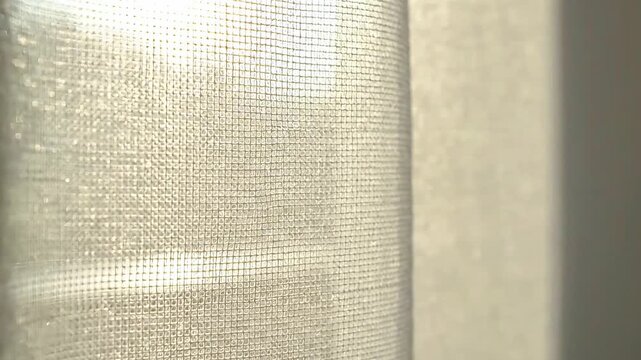 White sheer linen curtain blowing gently with glowing backlit dust motes
