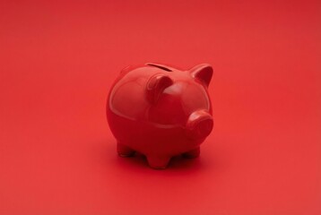 Red piggy bank sits on red surface against plain red background
