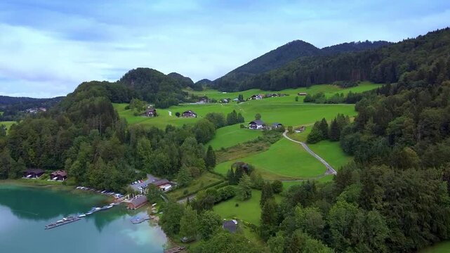Idyllic alpine village nestled in green rolling hills beside a clear turquoise lake