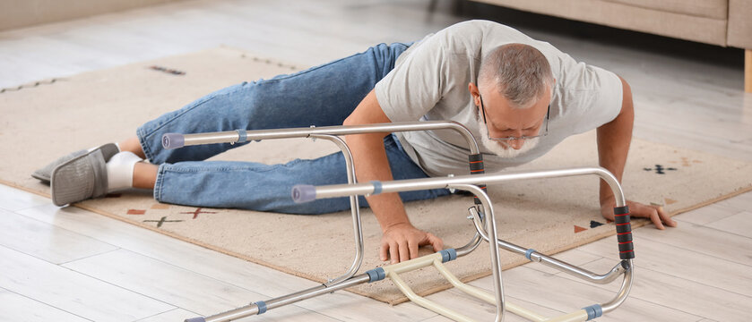 Senior man lying on carpet after fall with walker at home