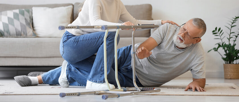 Young woman and grandfather lying on floor after fall with walker at home