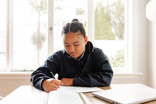 Teenage Samoan girl doing her homework on the table